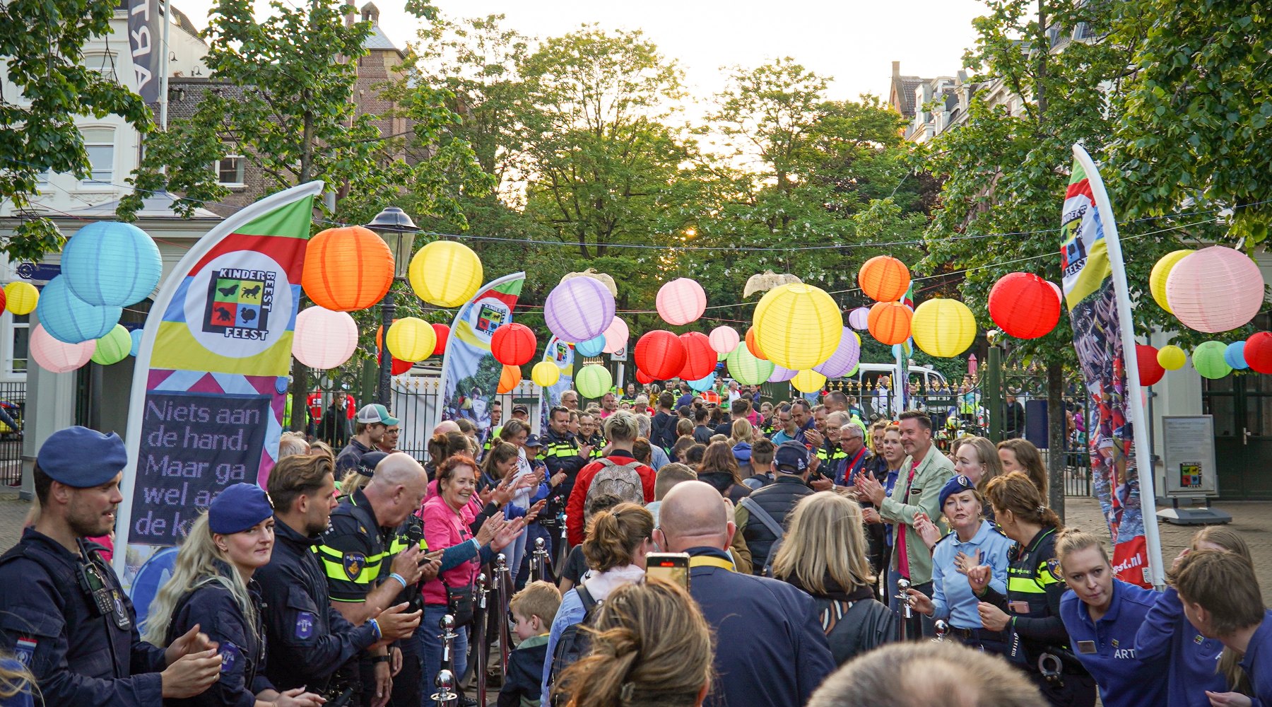 Vrijwilligers klappen en juichen voor een rode loper vol met bezoekers