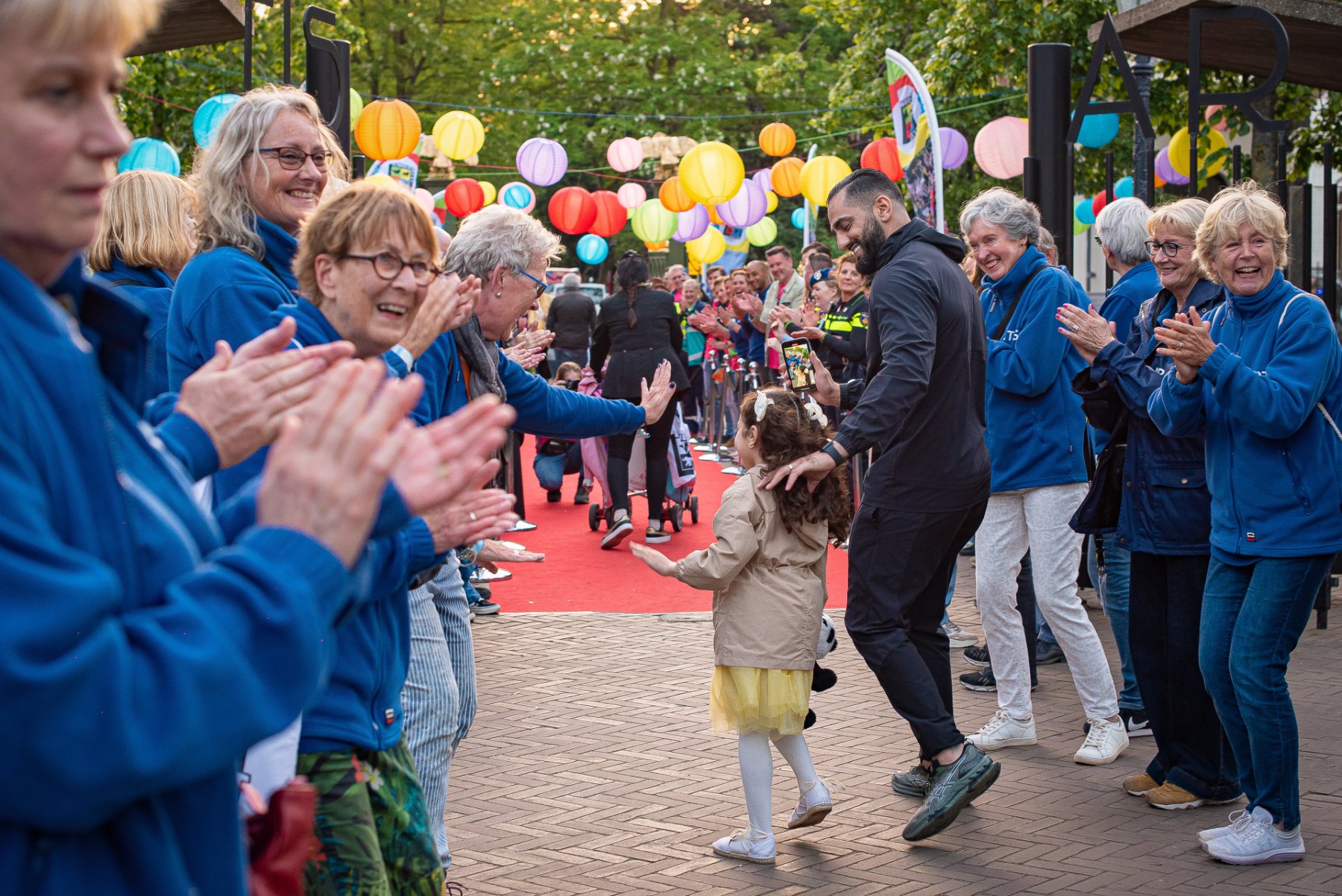 Vrijwilliger geeft meisje high five voordat ze met haar vader de rode loper op gaat 