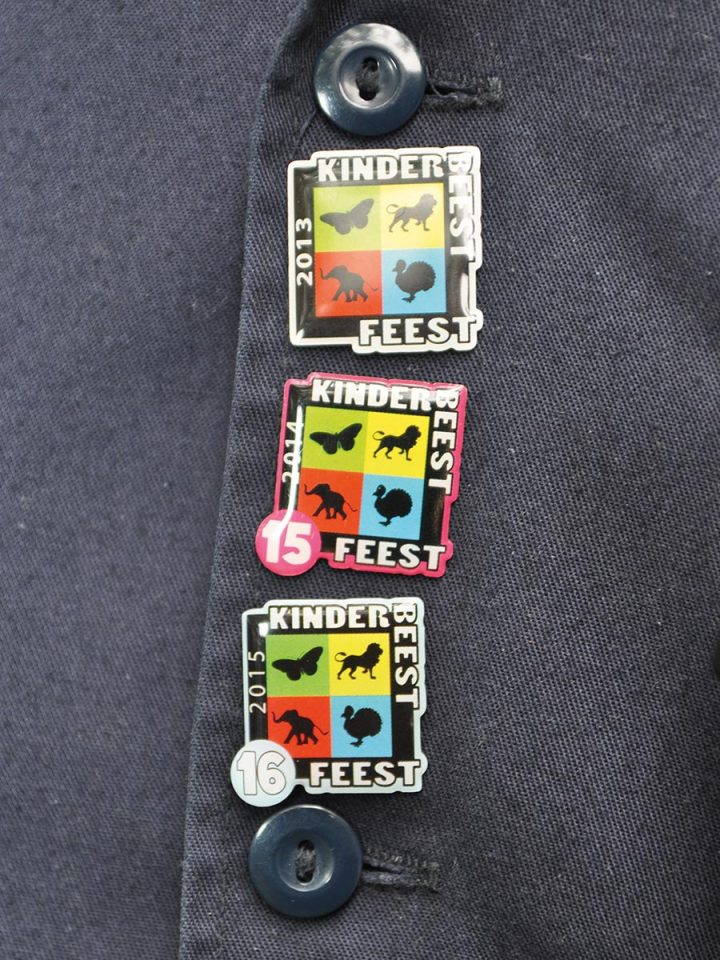 drie vrijwilligers speldjes van verschillende edities van het kinderbeestfeest