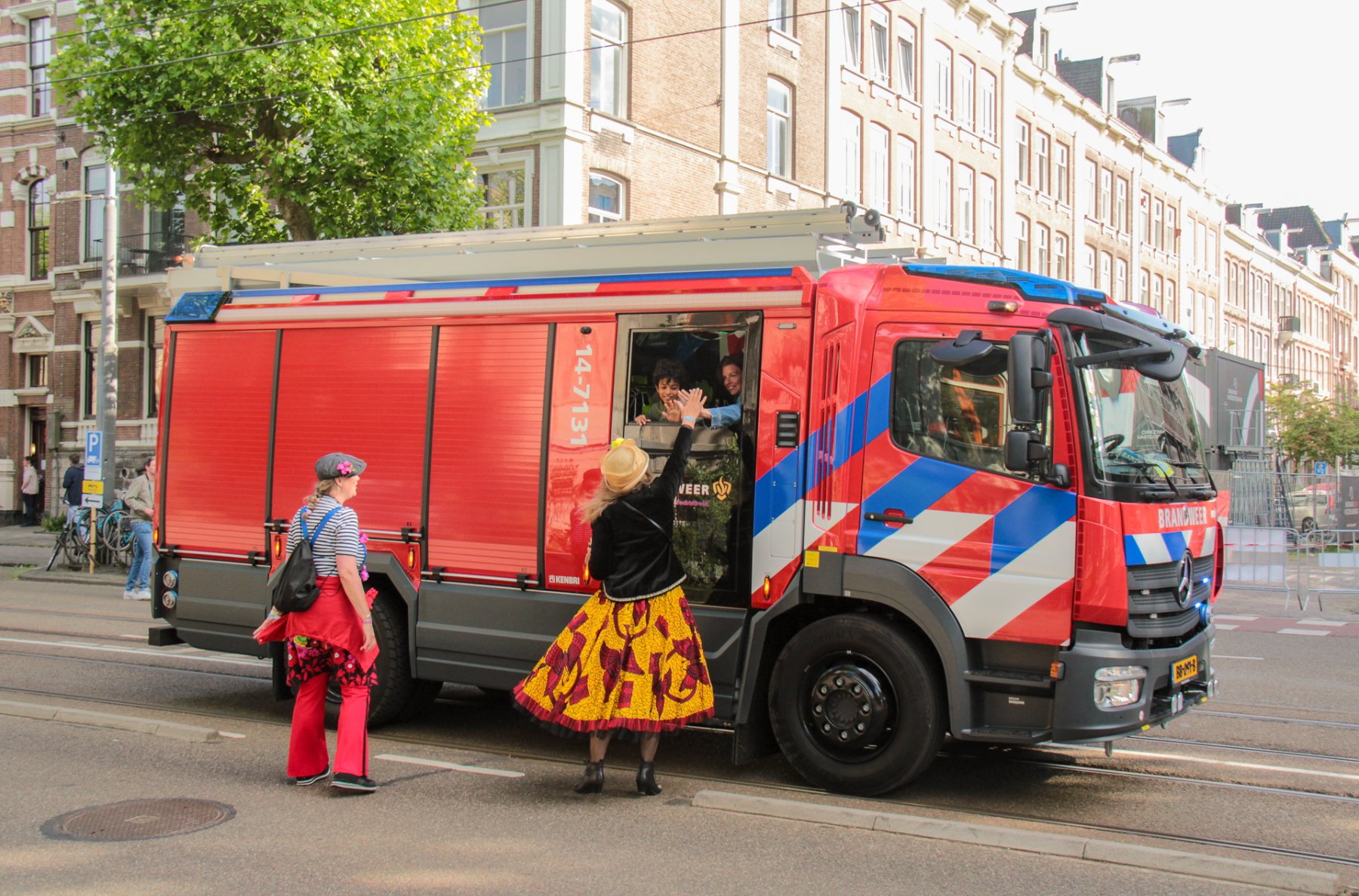 Kindje in brandweerauto zwaait naar vrijwilliger