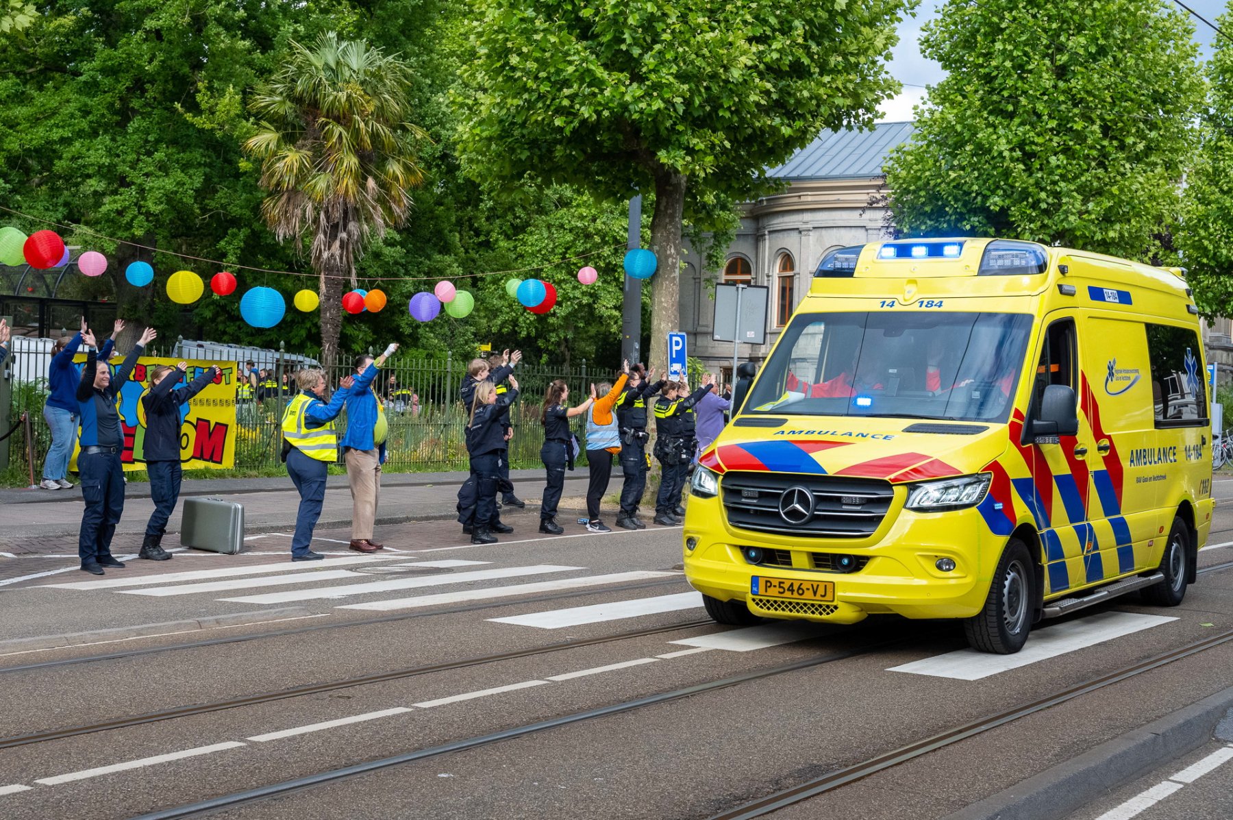 Vrijwilligers zwaaien naar aanrijdende ambulance